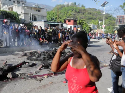 SENSITIVE MATERIAL. THIS IMAGE MAY OFFEND OR DISTURB People stand near the remains of alleged gang members after they were set on fire by a crowd of people, when trying to drive away, in Port-au-Prince, Haiti April 24, 2023. REUTERS/Ralph Tedy Erol