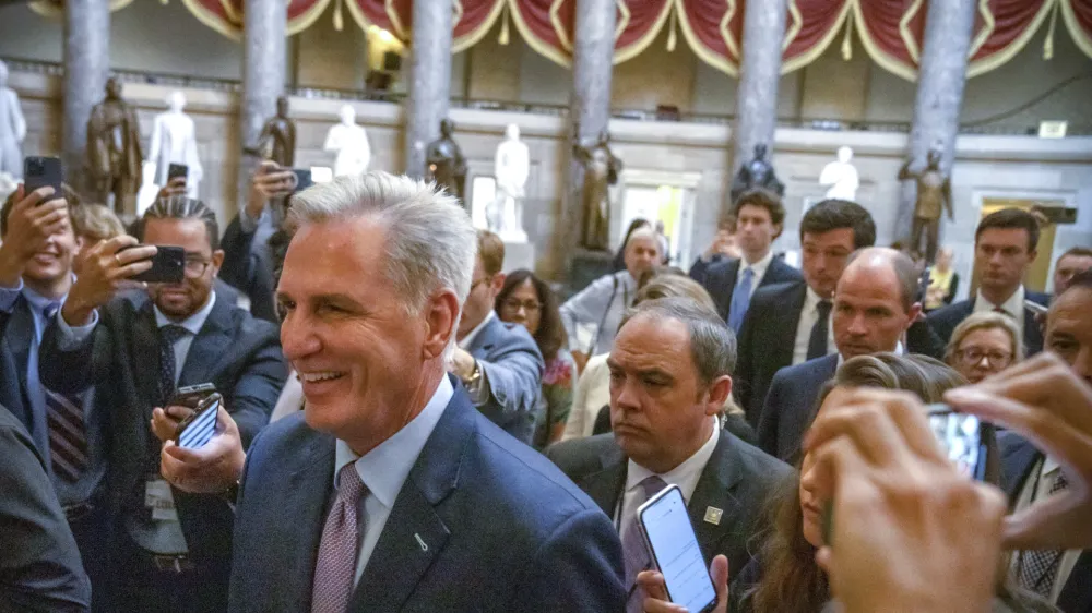 Speaker of the House Kevin McCarthy, R-Calif., is surrounded by police and press on the way to the chamber, at the Capitol in Washington, Tuesday, Oct. 3, 2023. McCarthy's ability to remain in leadership is now seriously at risk after the House voted to move ahead with an effort by hard-right Republican critics to oust him. Tuesday's narrow vote was forced by McCarthy's chief rival, Rep. Matt Gaetz of Florida. (AP Photo/Mark Schiefelbein)