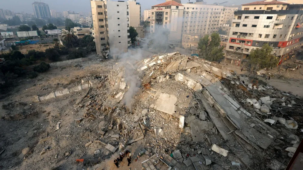 Palestinians inspect the ruins of Watan Tower, which was destroyed in Israeli strikes, in Gaza City October 8, 2023. REUTERS/Mohammed Salem