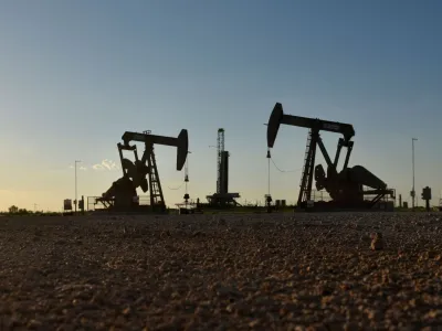 FILE PHOTO: FILE PHOTO: Pump jacks operate in front of a drilling rig in an oil field in Midland, Texas U.S. August 22, 2018. REUTERS/Nick Oxford/File Photo