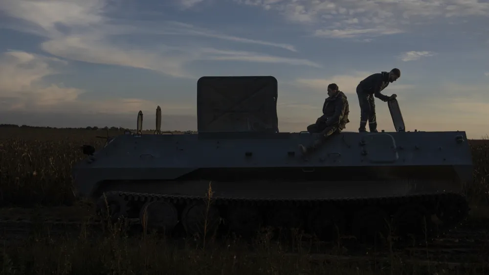 Workers of repair center are seen on the top of repaired MT-LB armored personnel carrier while testing it, in the Kyiv region, Ukraine, Tuesday, Oct. 24, 2023. (AP Photo/Alex Babenko)