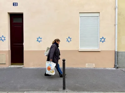 A woman walks past a building tagged with Stars of David in Paris, France, October 31, 2023. REUTERS/Lucien Libert