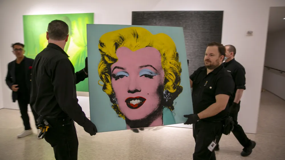 The 1964 painting Shot Sage Blue Marilyn by Andy Warhol is carried in Christie's showroom in New York City on Sunday, May 8, 2022. The auction house predicts it will sell for $200 million on Monday, becoming the most expensive 20th-century artwork to sell at auction. (AP Photo/Ted Shaffrey)