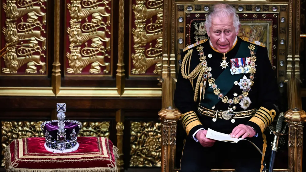 Britain's Prince Charles reads the Queen's speech as he sits by the The Imperial State Crown in the House of Lords Chamber, flanked by Britain's Prince William, left, and Camilla, Duchess of Cornwall, during the State Opening of Parliament, in the Houses of Parliament, in London, Tuesday, May 10, 2022. Britain's Conservative government made sweeping promises to cut crime, improve health care and revive the pandemic-scarred economy as it laid the laws it plans in the next year in a tradition-steeped ceremony known as the Queen's Speech -- but without a key player, Queen Elizabeth II, absent for the first time in six decades. The 96-year-old monarch pulled out of the ceremonial State Opening of Parliament because of what Buckingham Palace calls "episodic mobility issues." Her son and heir, Prince Charles, stood in, rattling through a short speech laying out 38 bills the government plans to pass. (Ben Stansall/Pool Photo via AP)