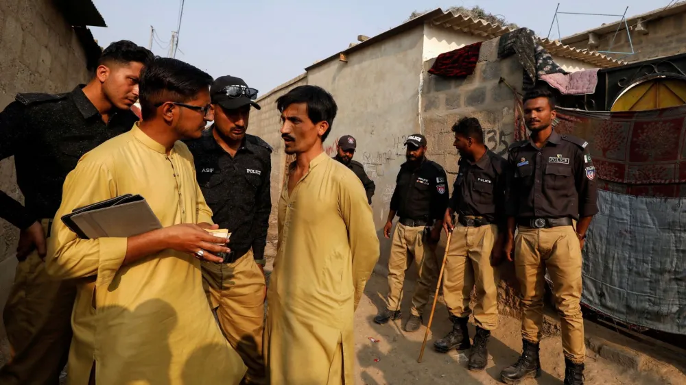 A worker from the National Database and Registration Authority (NADRA), along with police officers, speaks to an Afghan citizen while checking identity cards, during a door-to-door search and verification drive for undocumented Afghan nationals, in an Afghan Camp on the outskirts of Karachi, Pakistan, November 21, 2023. REUTERS/Akhtar Soomro