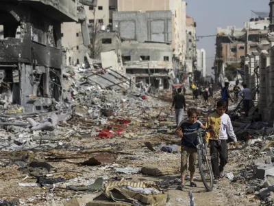 Palestinians walk through destruction in Gaza City on Friday, Nov. 24, 2023, as the temporary cease-fire between Israel and Hamas took effect. (AP Photo/Mohammed Hajjar)