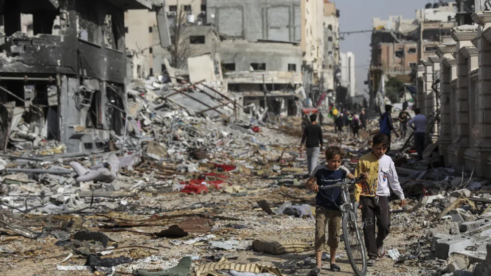 Palestinians walk through destruction in Gaza City on Friday, Nov. 24, 2023, as the temporary cease-fire between Israel and Hamas took effect. (AP Photo/Mohammed Hajjar)