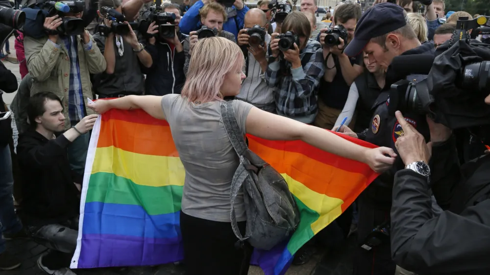 FILE - A gay rights activist stands with a rainbow flag, in front of journalists, during a protesting picket at Dvortsovaya (Palace) Square in St.Petersburg, Russia, Sunday, Aug. 2, 2015. Russia's Supreme Court on Thursday, Nov. 30, 2023, effectively outlawed LGBTQ+ activism, in the most drastic step against advocates of gay, lesbian and transgender rights in the increasingly conservative country. (AP Photo, File)