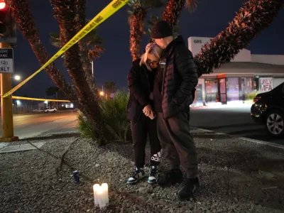 Sean Hathcock, right, kisses Michelle Ashley after the two left candles for victims of a shooting at the University of Nevada, Las Vegas, Wednesday, Dec. 6, 2023, in Las Vegas. The two graduated from the school and live nearby. (AP Photo/John Locher)