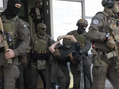 Kosovo police members of Special Intervention Unit escort one of the arrested Serb gunmen out of the court after the Kosovo shootout in capital Pristina, on Tuesday, Sept. 26, 2023. (AP Photo/Visar Kryeziu)