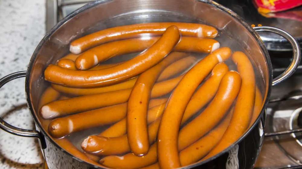 sausages are boiling in a pot of water