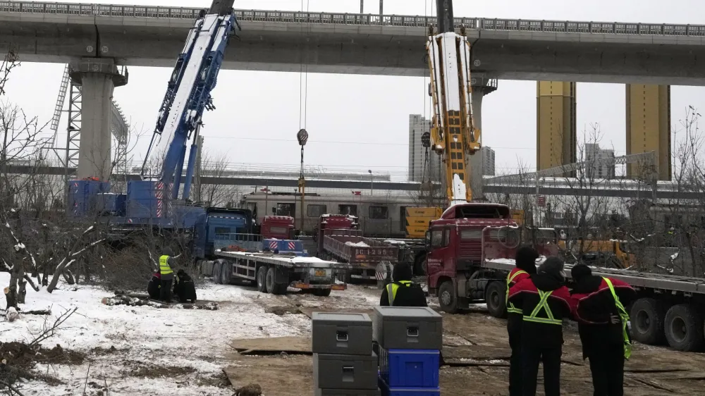 Police officers watch over near the site of train collision on the western district in Beijing, Friday, Dec. 15, 2023. Two subway trains have collided in heavy snow in Beijing, sending over 500 people to the hospital, including more than 100 with broken bones. Authorities said Friday the accident occurred the previous evening in Beijing's mountainous west on an above-ground portion of the sprawling subway system's Changping line. (AP Photo/Ng Han Guan)