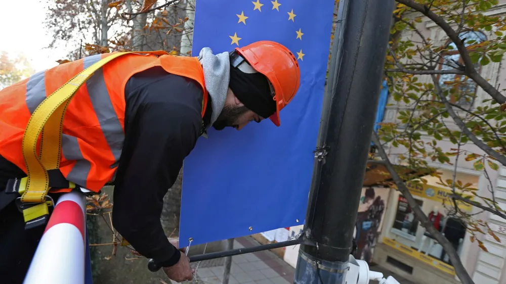 Worker Goga Akhvlediani hangs a banner with a European Union flag on a street in Tbilisi, Georgia December 15, 2023. REUTERS/Irakli Gedenidze