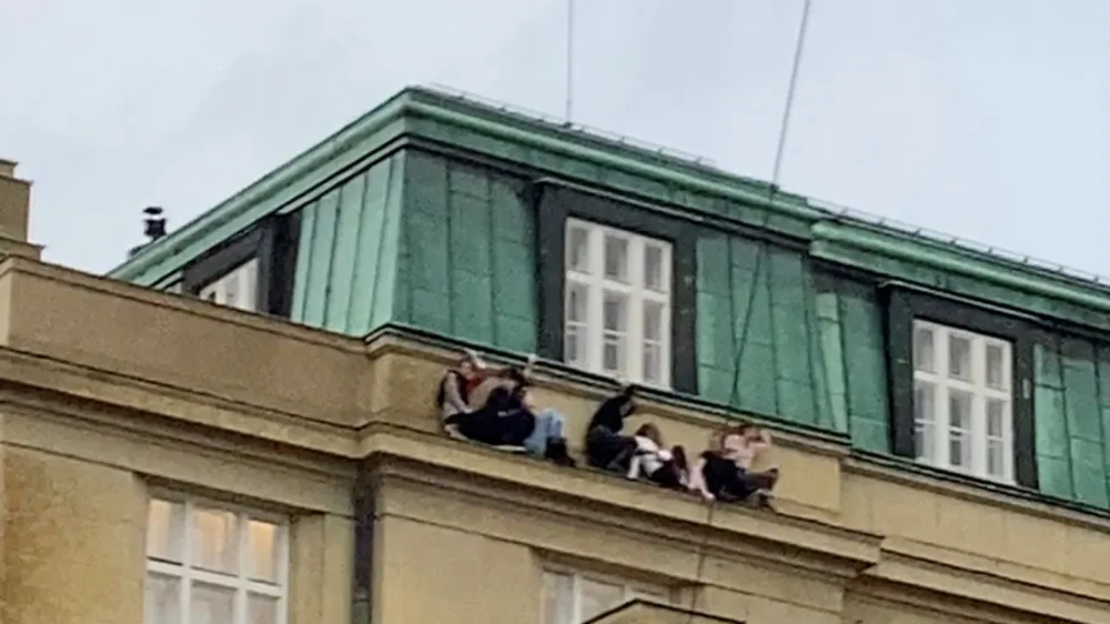 People watch from a roof following a shooting at one of the buildings of Charles University, in Prague, Czech Republic, December 21, 2023, as seen in this screen grab taken from a social media video. Ivo Havranek/via REUTERS THIS IMAGE HAS BEEN SUPPLIED BY A THIRD PARTY. MANDATORY CREDIT. NO RESALES. NO ARCHIVES.