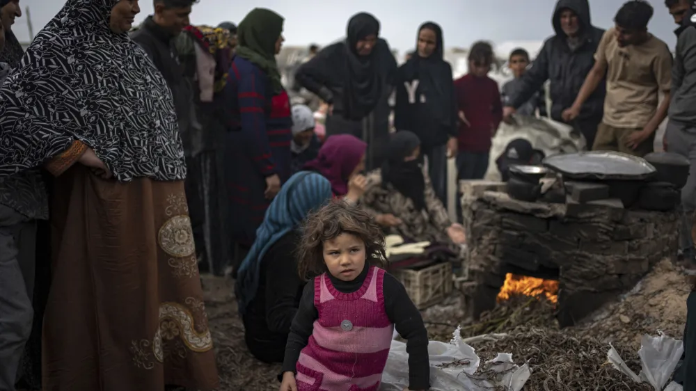 A little girl sits as Palestinians displaced by the Israeli bombardment wait for their turn to bake bread at the makeshift tent camp in the Muwasi area in Rafah, Gaza Strip, Saturday, Dec. 23, 2023. (AP Photo/Fatima Shbair)