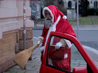 24 December 2023, Saxony, Leipzig: Andre Adelinia gets out of his car in the role of Santa Claus to give presents to children. He has been working as Santa Claus for children in his circle of friends for 15 years. Photo: Sebastian Willnow/dpa