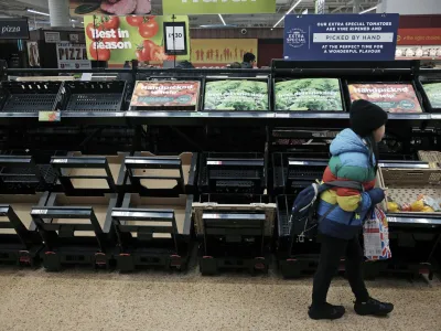 A girl walks by empty fruit and vegetable shelves at an Asda in east London, Saturday, Feb. 25, 2023. British people have had to ration tomatoes and cucumbers for the past two weeks amid a shortage of fresh vegetables. Officials blame the problem on recent bad weather in Spain and North Africa, but with other European countries not suffering the same shortages, some people question if Brexit is to blame. (Yui Mok/PA via AP)