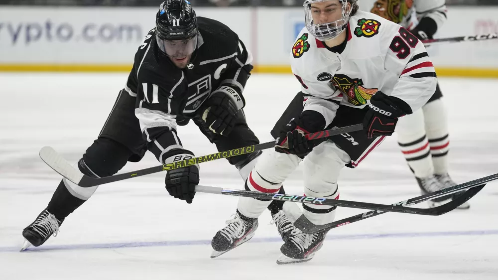 Los Angeles Kings center Anze Kopitar (11) and Chicago Blackhawks center Connor Bedard (98) reach for the puck during the third period of an NHL hockey game Thursday, April 18, 2024, in Los Angeles. (AP Photo/Ashley Landis)