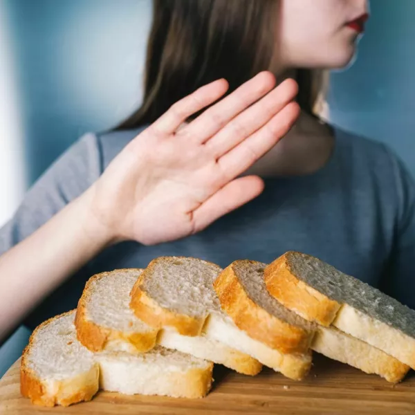 Gluten intolerance concept. Young girl refuses to eat white bread - shallow depth of field - selective focus on bread / Foto: Wojciech Kozielczyk