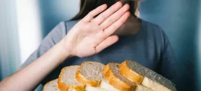 Gluten intolerance concept. Young girl refuses to eat white bread - shallow depth of field - selective focus on bread / Foto: Wojciech Kozielczyk