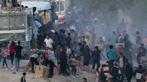 Palestinians climb onto trucks to grab aid that was delivered into Gaza through a U.S.-built pier, amid the ongoing conflict between Israel and the Palestinian Islamist group Hamas, as seen from central Gaza Strip, May 18, 2024. REUTERS/Ramadan Abed   TPX IMAGES OF THE DAY