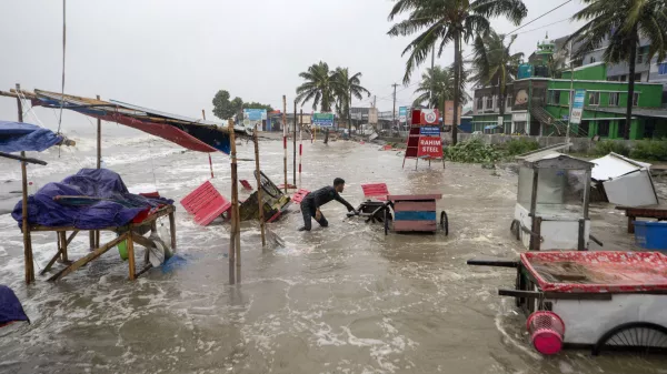 A man salvages a cart and other material as water flows on to the Kuakata beach on the coast of Bay of Bengal caused by the advancing Cyclone Remal in Barisal, Bangladesh, Sunday, May 26, 2024. (AP Photo/Abdul Goni)