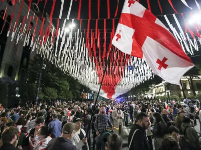 Demonstrators with a Georgian national flag gather at the Parliamentary building during an opposition protest against the foreign influence bill in Tbilisi, Georgia, Tuesday, May 28, 2024. The Georgian parliament has overridden a presidential veto of the "foreign agents" legislation that has fueled Western concerns and sparked massive protests for weeks. (AP Photo/Zurab Tsertsvadze)