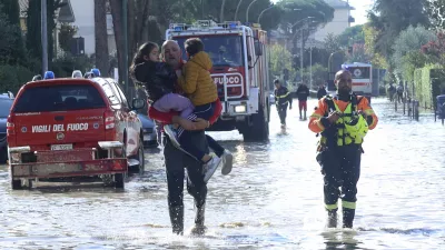 A man carries children through flood water, with emergency services at the scene after heavy rainfall, in Tuscany, Italy, Saturday, Nov. 4, 2023. Record-breaking rain provoked floods in a vast swath of Tuscany as storm Ciarán pushed into Italy overnight. At least six people were killed in that central Italian region. (Adriano Conte/LaPresse via AP)