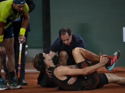 Germany's Alexander Zverev holds his right ankle after twisting it, as Spain's Rafael Nadal, left, looks on during their semifinal match at the French Open tennis tournament in Roland Garros stadium in Paris, France, Friday, June 3, 2022. (AP Photo/Christophe Ena)