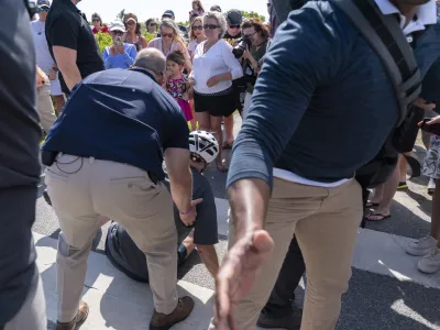 President Joe Biden is helped by U.S. Secret Service agents after he fell trying to get off his bike to greet a crowd on a trail at Gordons Pond in Rehoboth Beach, Del., Saturday, June 18, 2022. (AP Photo/Manuel Balce Ceneta)