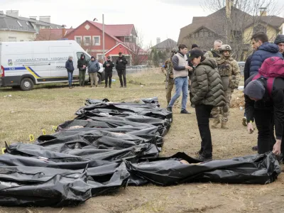 Ukrainian Prosecutor General Iryna Venediktova, center, looks at the exhumed bodies of civilians killed during the Russian occupation in Bucha, on the outskirts of Kyiv, Ukraine, Friday, April 8, 2022. An international organization formed to identify the dead and missing from the 1990s Balkan conflicts is preparing to send a team of forensics experts to Ukraine as the death toll mounts more than six weeks into the war caused by Russia's invasion. (AP Photo/Efrem Lukatsky)