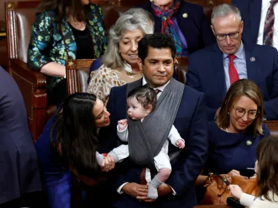 U.S. Rep. Alexandria Ocasio-Cortez (D-NY) talks to the infant child of Rep. Jimmy Gomez (D-CA) inside the House Chamber during votes for the next Speaker of the House on the first day of the 118th Congress at the U.S. Capitol in Washington, U.S., January 3, 2023. REUTERS/Evelyn Hockstein