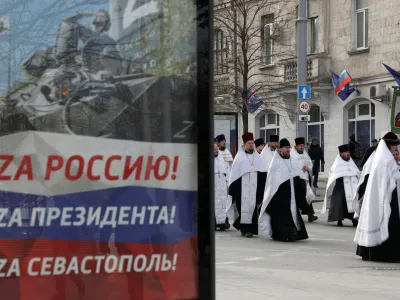 Clergymen walk past a board, displaying slogans with symbols "Z" in support of the Russian armed forces involved in the country's military campaign in Ukraine, during a religious procession to celebrate Orthodox Christmas in Sevastopol, Crimea, January 7, 2023. Slogans on a board read: "To Russia! To President! To Sevastopol!" REUTERS/Alexey Pavlishak