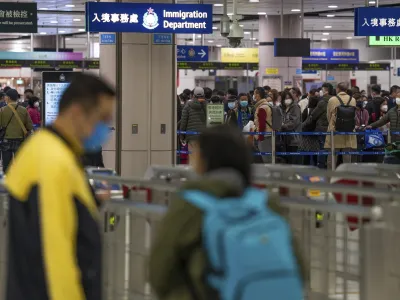 FILE - Travelers wearing face masks line up at the immigration counters of the departure hall at Lok Ma Chau station following the reopening of crossing border with mainland China, in Hong Kong, Sunday, Jan. 8, 2023. Hong Kong authorities announced Friday, Feb. 3, 2023, that they will lift a quota on the number of cross-border travelers with China and scrap mandatory COVID-19 PCR testing requirements as both places seek to drive economic growth. (AP Photo/Bertha Wang, File)