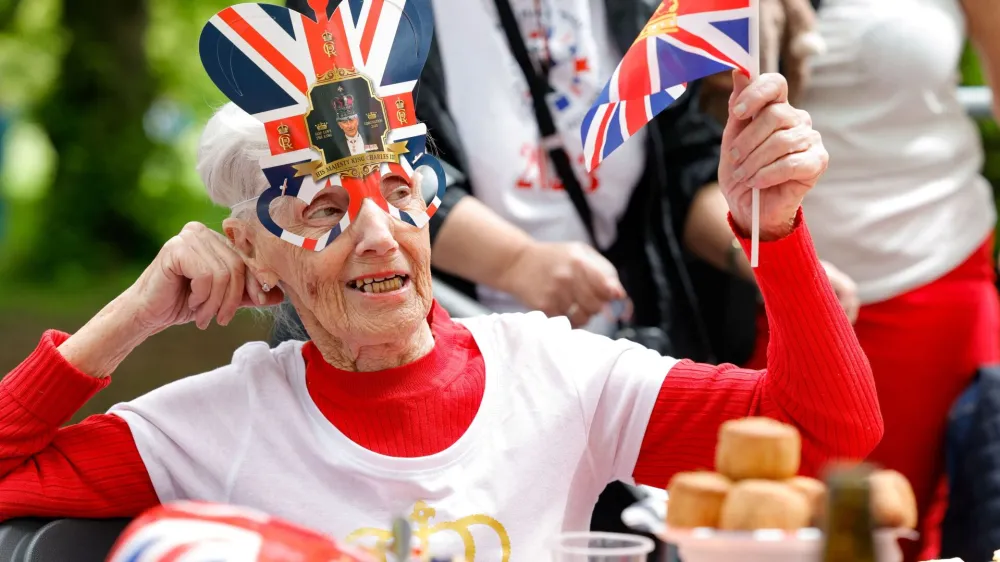 A woman waves a Union Jack flag as people celebrate Britain's King Charles' coronation with the Big Lunch at Regent's Park, in London, Britain, May 7, 2023. REUTERS/Piroschka Van De Wouw