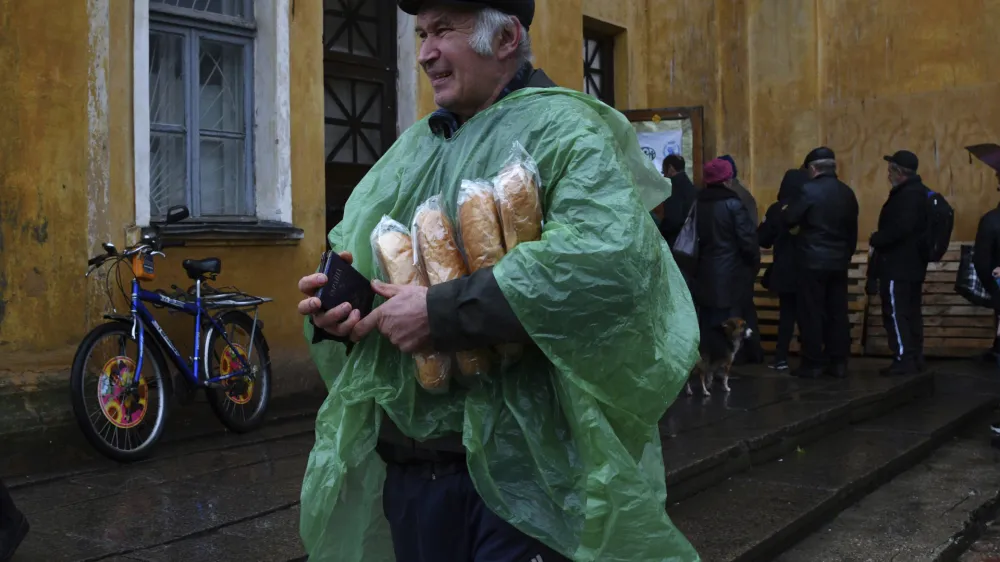 A man carries Ukrainian passport and bread after receiving it at humanitarian aid center in Kramatorsk, Ukraine, Wednesday, Oct. 26, 2022. (AP Photo/Andriy Andriyenko)