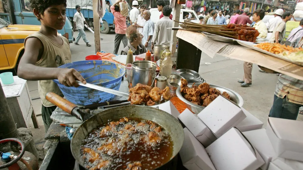 Saddam, 13, works at a roadside food stall in the eastern Indian city of Kolkata October 10, 2006. A ban on child labour in households, restaurants, hotels and resorts came into effect in India on Tuesday. Officials hope the new ban, which will apply to children under 14, will protect underage workers from psychological and sexual abuse as well as from strenuous working conditions. REUTERS/Parth Sanyal (INDIA)