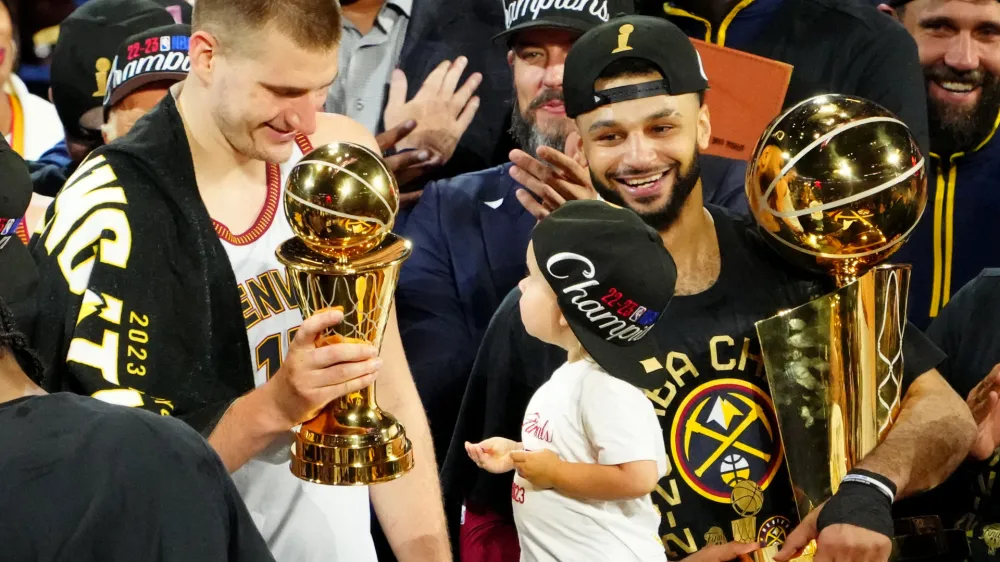 Jun 12, 2023; Denver, Colorado, USA; Denver Nuggets center Nikola Jokic (15) celebrates with the Bill Russell NBA Finals MVP Award as guard Jamal Murray (27) holds the Larry O'Brien Trophy after the Nuggets won the 2023 NBA Championship against the Miami Heat at Ball Arena. Mandatory Credit: Ron Chenoy-USA TODAY Sports