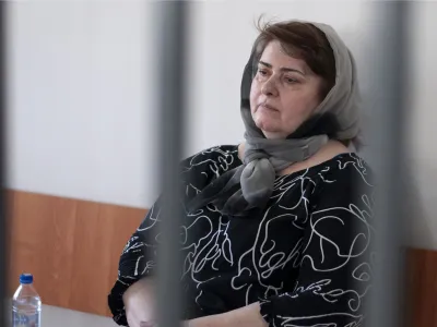 Zarema Musayev sits behind bars in a courtroom a in Grozny, Russia, Tuesday, July 4, 2023. Musayev is the mother of two local activists who have challenged Chechen authorities and has been in custody in Chechnya since her arrest in January 2022. Unidentified masked assailants in the Russian province of Chechnya attacked and beat Novaya Gazeta journalist Elena Milashina and lawyer Alexander Nemov on Tuesday, who had just arrived in Chechnya to attend the trial of Musayeva. (AP Photo)