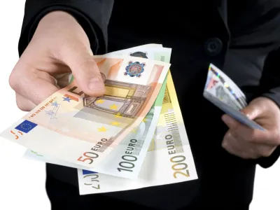 Hand giving Euro banknotes of 50, 100 and 200 Euro with another hand in the background keeping the spare. Isolated.Studio shot.