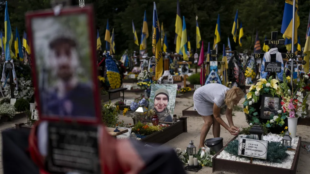 Natalie Zaichenko, 60, tends to the grave of her son, a Ukrainian soldier who was killed in the war against Russia, in Kyiv, Ukraine, Thursday, Aug. 3, 2023. (AP Photo/Jae C. Hong)