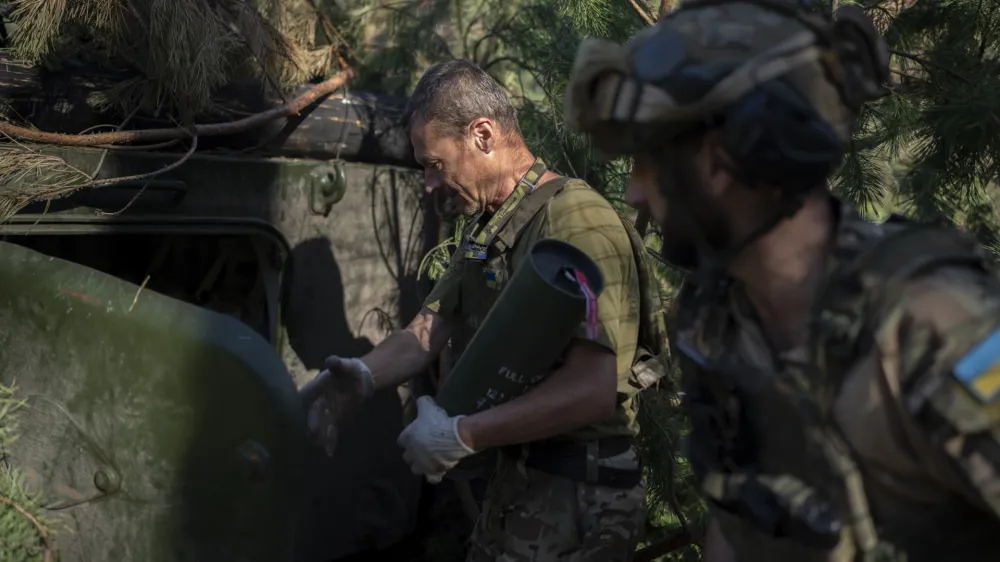 Ukrainian soldiers load a howitzer with a shell on the front line in the outskirts of Lyman, Ukraine, Tuesday, Aug. 15, 2023. Moscow's army is staging a ferocious push in northeast Ukraine designed to distract Ukrainian forces from their counteroffensive and minimize the number of troops Kyiv is able to send to more important battles in the south. (AP Photo/Bram Janssen)