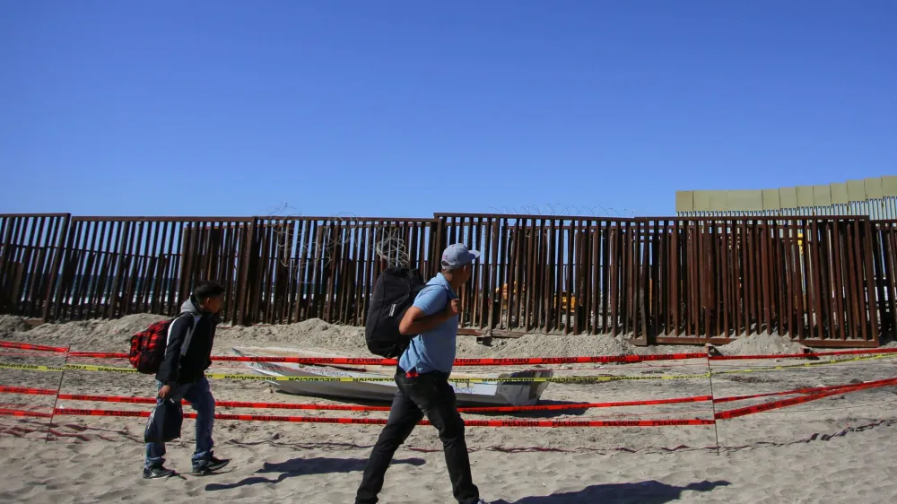 Migrants walk near the border fence, at Playas de Tijuana, in Tijuana, Mexico October 2, 2023. REUTERS/Jorge Duenes