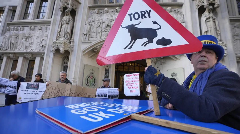 Protesters stand outside the Supreme Court in London, Wednesday, Nov. 15, 2023. Britain's Supreme Court has ruled that the government's contentious plan to send some migrants on a one-way trip to Rwanda is illegal. (AP Photo/Kirsty Wigglesworth)