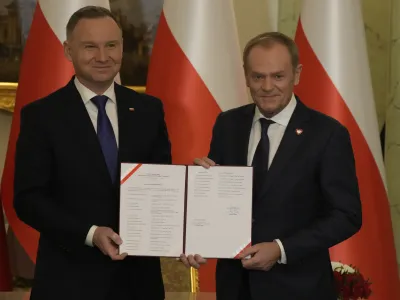 Poland's new Prime Minister Donald Tusk, right, and Poland's President Andrzej Duda pose for cameras during the swearing-in ceremony at the presidential palace in Warsaw, Poland, Wednesday, Dec. 13, 2023. Donald Tusk was sworn in by the president in a ceremony where each of his ministers was also taking the oath of office. (AP Photo/Czarek Sokolowski)