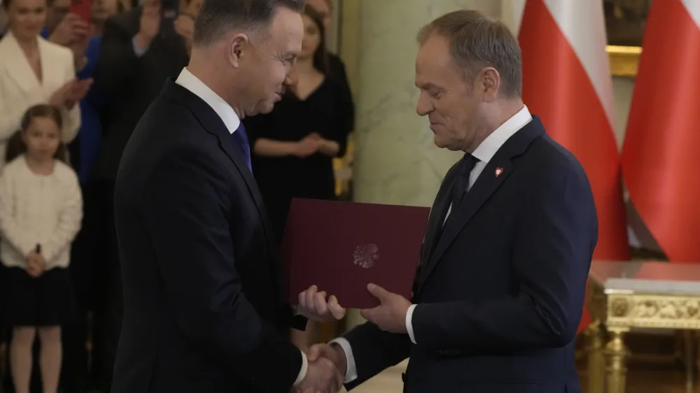 Poland's new Prime Minister Donald Tusk, right, shakes hands with Poland's President Andrzej Duda during the swearing-in ceremony at the presidential palace in Warsaw, Poland, Wednesday, Dec. 13, 2023. Donald Tusk was sworn in by the president in a ceremony where each of his ministers was also taking the oath of office. (AP Photo/Czarek Sokolowski)