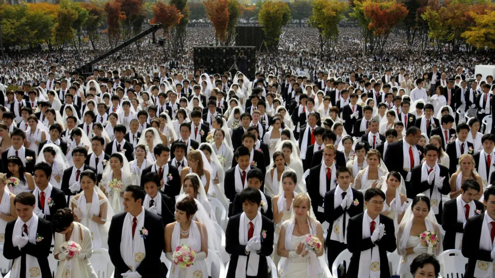 Couples from around the world participate in a mass wedding ceremony arranged by the Rev. Sun Myung Moon's Unification Church at Sun Moon University in Asan, south of Seoul, South Korea, Wednesday, Oct. 14, 2009. The brides wore wedding dresses or their national dress; the men wore black suits with red ties, with white scarves around their necks. (AP Photo/Lee Jin-man)