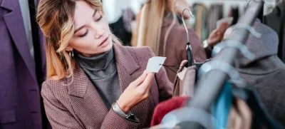 Check price. Elegant fashionable businesswoman shopping on weekend checking the price of dress / Foto: Yacobchuk