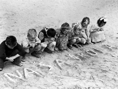 Okoli leta 1946 v Egiptu jugoslovanski otroci gledajo srbohrvaške besede "naša škola" (naša šola), ki so jih zapisali v pesek, v begunskem taborišču Uprave združenih narodov za pomoč in obnovo (UNRRA) v Tolumbatu. UNRRA je delovala med leti 1943 in 1949, nato pa je bil njen mandat vključen v dolgoročno razvojno delo drugih agencij Združenih narodov. Delo UNRRA za otroke je prevzel Unicef. / Foto: arhiv Unicef / Foto: Arhiv Unicef