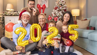 Beautiful happy family celebrating Christmas at home, having fun holding giant balloons shaped as numbers 2025, representing the upcoming New Year / Foto: Vladans